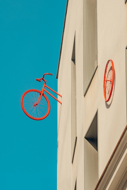 Tylna połowa zabytkowego roweru i czerwone koło przypięte do ściany minimalistycznego bloku konstrukcyjnego