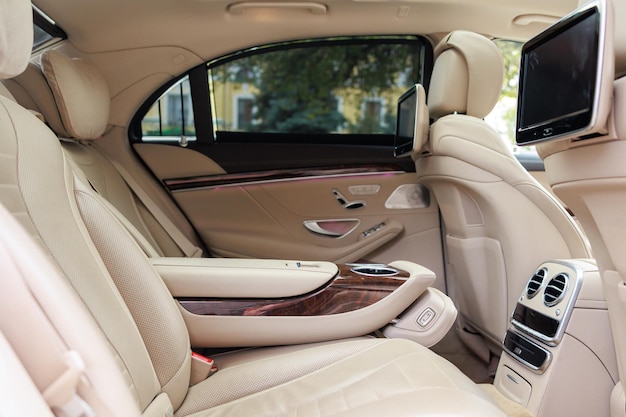 Tylne siedzenia luksusowego samochodu z prawdziwego drewna i skóry oraz ekran multimedialny