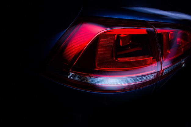 Tylne światła samochodu z błyszczącą powierzchnią, czerwone podświetlenie mocnego nadwozia sportowego sedana, koncepcja.