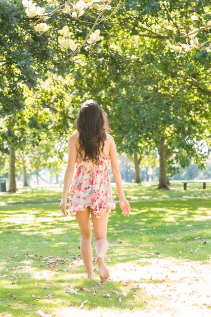 Tylni widok elegancki brunetki odprowadzenie na trawie