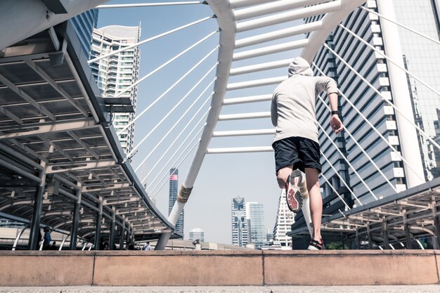 Zdjęcie tylni widok młody sportowy mężczyzna jogging na miasto moscie