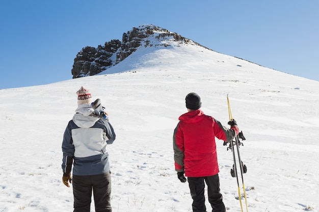 Tylni widok para z narciarskimi deskami na śniegu