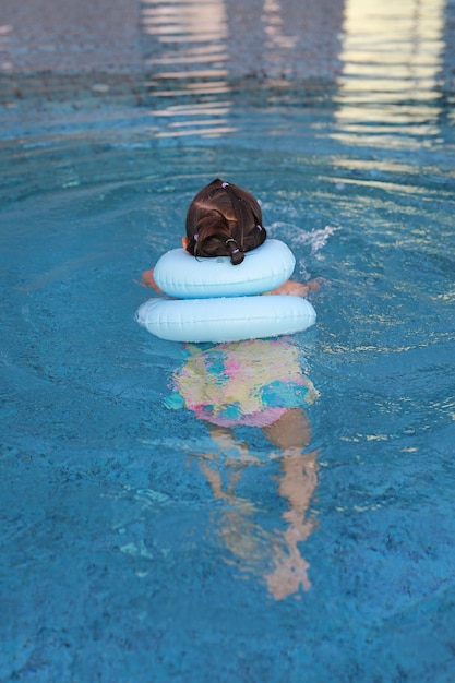 Tylni widoku mała dziewczynka bawić się w nadmuchiwanym dziecko basenie.