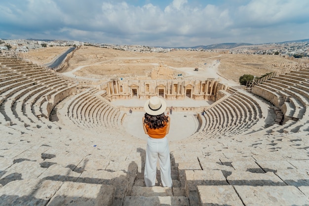 Tylny widok Azjatycka młodej kobiety pozycja przed Południowym rzymskim teatrem, Jerash, Jordania