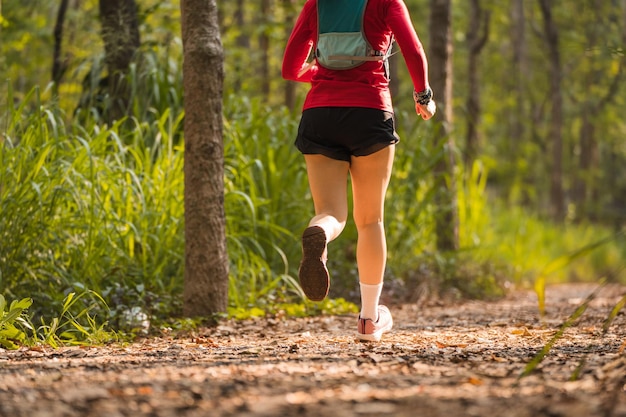 Tylny widok dorosłej Azjatki biegaczki z kamizelką do biegania ćwiczy bieganie po lesie