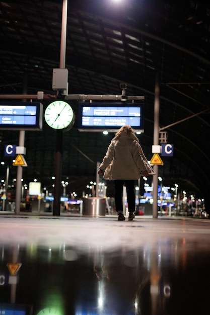 Zdjęcie tylny widok kobiety stojącej na stacji kolejowej
