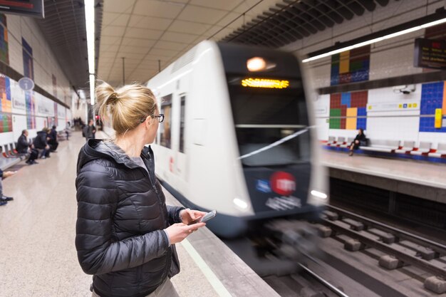 Tylny widok kobiety stojącej na stacji kolejowej