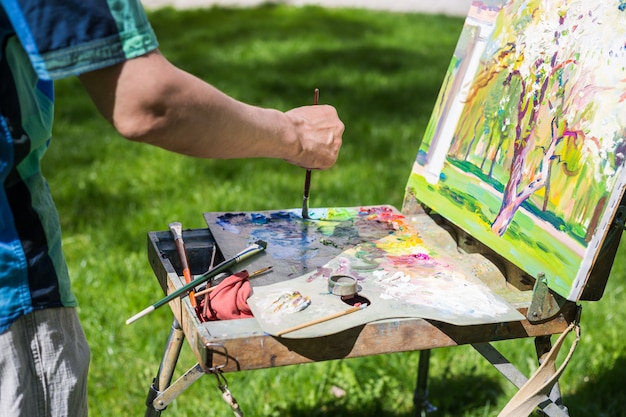 Tylny widok męski artysta pracuje outdoors w parku lub ogródzie