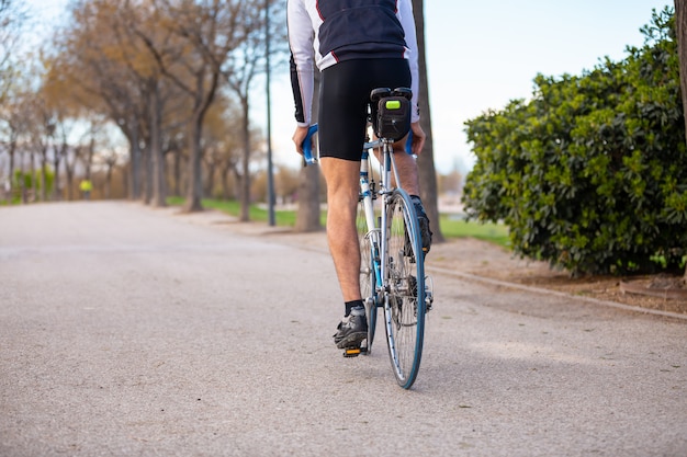 Tylny Widok Młody Męski Cyklista W Sportswear I Ochronnego Hełma Kolarstwa Jechać Na Rowerze Na Drodze W Parku