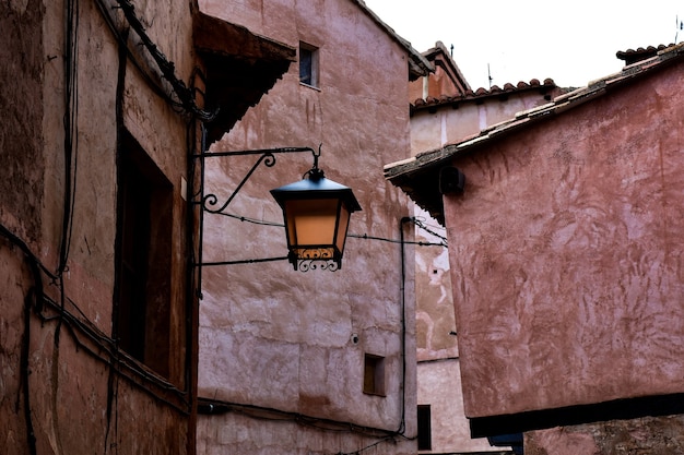Typowa wąska czerwonawa uliczka średniowiecznej wioski ze starą latarnią