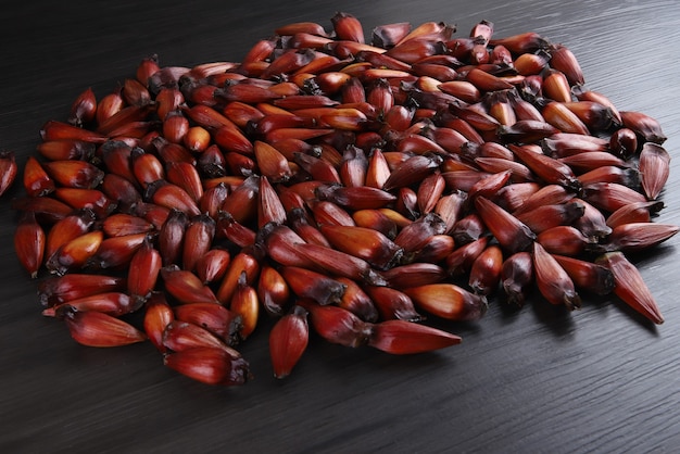 Typowe nasiona araukarii używane jako przyprawa w kuchni brazylijskiej zimą. Brazylijskie orzechy pinion w brązowej i czerwonej drewnianej misce na szarym drewnianym tle.