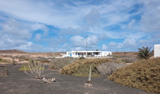 Typowy biały dom na wyspie La Graciosa, z pustynną roślinnością, Lanzarote, Wyspy Kanaryjskie, Hiszpania.