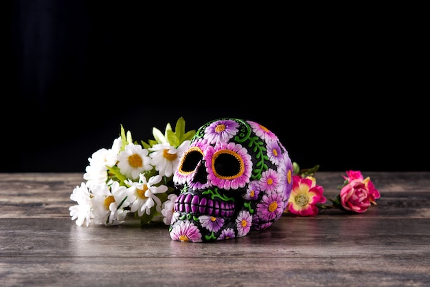 Typowy meksykański diadem czaszki i kwiaty na drewnianym stole. Dia de los muertos.