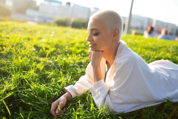 Tysiąclecia młoda kobieta blond krótkie włosy na zewnątrz uśmiechnięta leżała na trawie portret