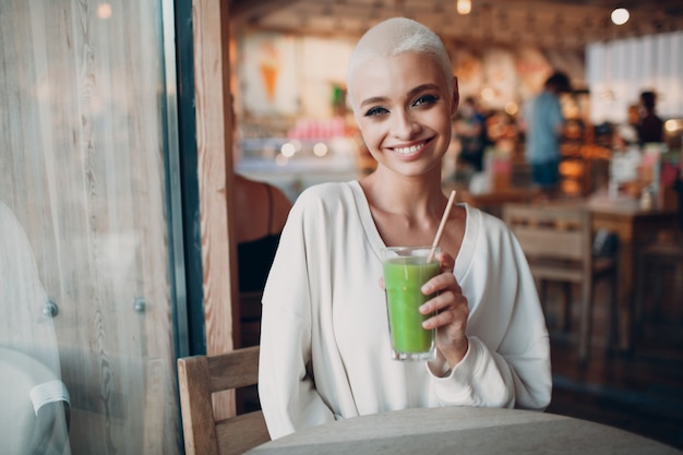 Tysiąclecia młoda kobieta blond krótkie włosy w pomieszczeniu z zielonym smoothie