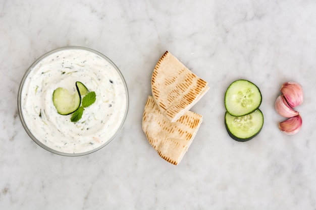 Tzatziki w misce i chleb pita na białym marmurze widok z góry