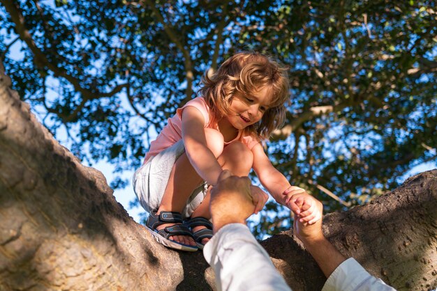 Ubezpieczenie dzieci dzieci wspinające się po drzewach Rodzic ochrony dziecka trzyma rękę dziecka