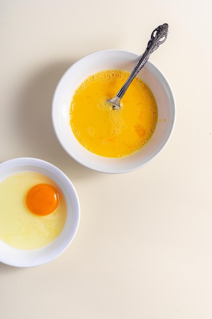 Ubijanie jaj Skorupka Jaj Surowe jajka w szklanej i białej misce na stole Płasko leżące Złamane Białe Tło