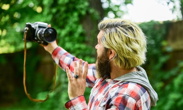 Zdjęcie uchwyć te wspomnienia lustrzanka hipster człowiek z brodą użyj profesjonalnego aparatu selfie czas fotograf trzymaj retro aparat dziennikarz to moja kariera reporter zrób zdjęcie rocznika aparatu