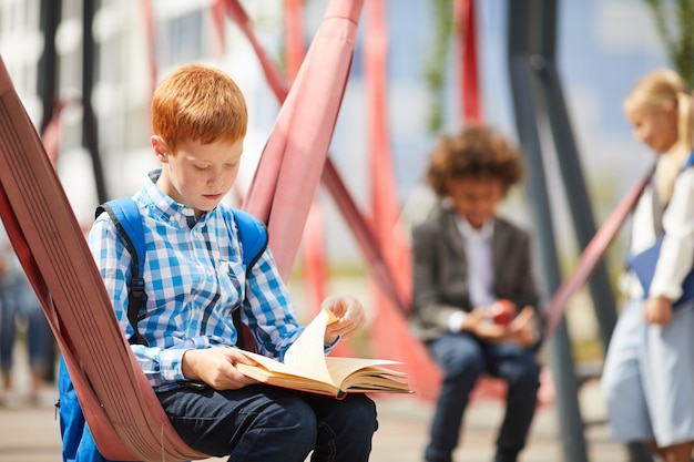 Uczeń czyta książkę na zewnątrz