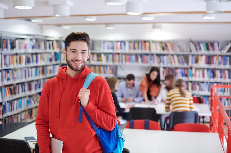 Zdjęcie uczeń korzysta z laptopa i szkolnej biblioteki