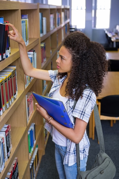 Uczeń podnosi książkę od półki w bibliotece