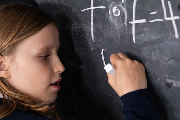 Zdjęcie uczeń rozwiązuje problem matematyczny stojąc przy tablicy w klasie