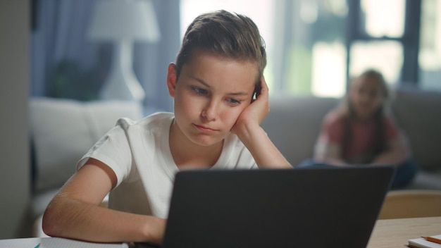 Zdjęcie uczeń używający laptopa do e-learningu w domu śliczny chłopiec ogląda lekcję wideo