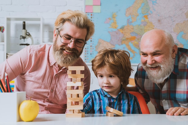 Uczeń z ojcem i dziadkiem bawią się razem w domu grając w jenga