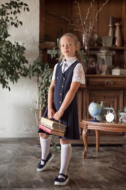 Uczennica dziewczyna w szkolnym mundurku, z książkami w dłoniach.