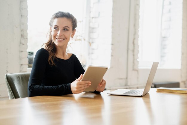 Uczennica freelancer pracująca w biurze przy użyciu miejsca coworkingowego do wynajęcia na laptopie