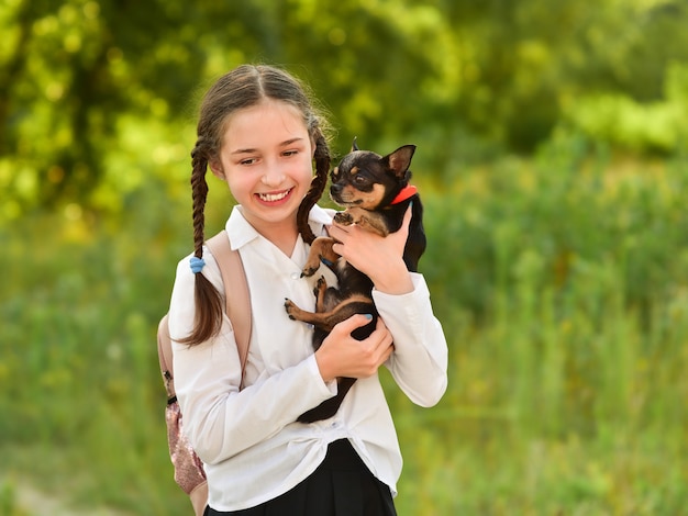 Uczennica i chihuahua w przyrodzie. Koncepcja dzieci i zwierząt. Zwierzak i dziewczyna