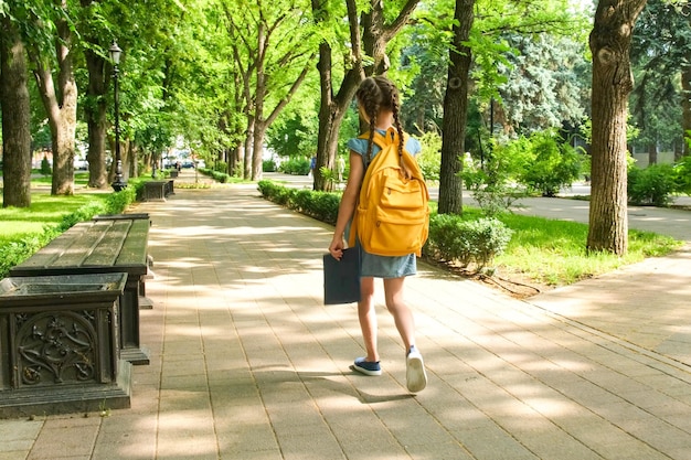 Zdjęcie uczennica idzie rano do szkoły przez park. edukacja, powrót do szkoły