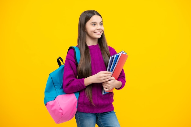 Uczennica nastoletnia studentka trzyma książkę na żółtym tle odizolowanego studia Koncepcja szkoły i edukacji Powrót do szkoły