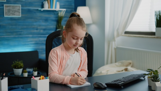 Uczennica pisze na notebooku z piórem do pracy domowej