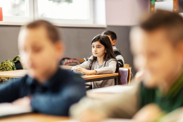 Uczennica po wykładzie z kolegami z klasy w szkole podstawowej