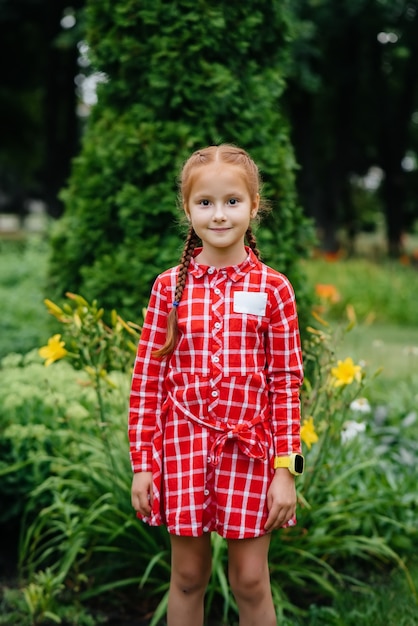 Uczennica stoi i uśmiecha się w parku na świeżym powietrzu. Powrót do szkoły, nauka w czasie pandemii.