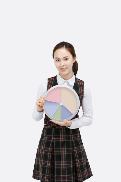 Uczennica szkoły średniej trzymająca okrągłą tablicę i projektująca harmonogram edukacji i planista studiów t