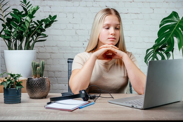 Uczennica w słuchawkach ogląda webinarium z klasą zoomu w wirtualnej klasie na swoim laptopie