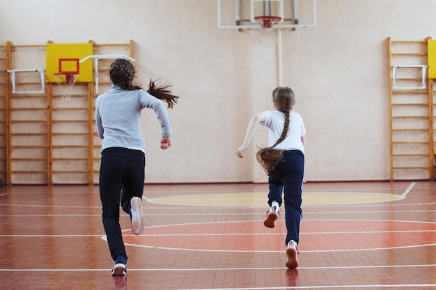 Uczniom szkół podstawowych zajęcia sportowe w pomieszczeniach. Dzieci biegają i grają w gry mobilne.