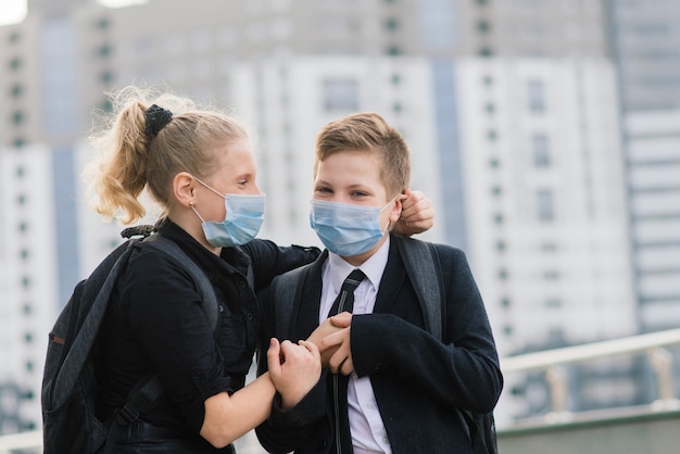 Uczniowie, Chłopiec I Dziewczynka W Maskach Medycznych Spacerują Po Mieście.