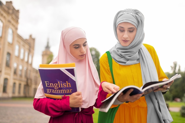 Uczniowie powtarzający język angielski. Zajęci międzynarodowi studenci muzułmańscy powtarzający angielski podczas chodzenia na zajęcia