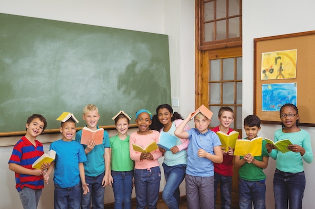 Uczniowie stojący z książkami na głowach w szkole podstawowej