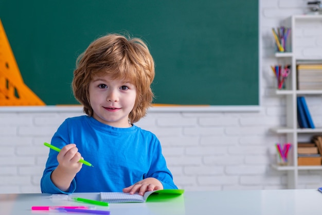 Uczniowie szkoły podstawowej uczą się słodkiego chłopca w klasie w pobliżu tablicy tablica tablica c