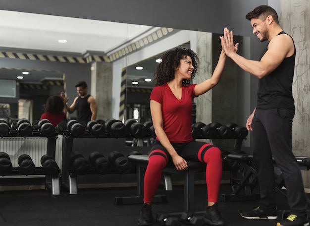 Udane szkolenie. Trener fitness i kobieta przybijają sobie piątkę po treningu na siłowni, kopia przestrzeń