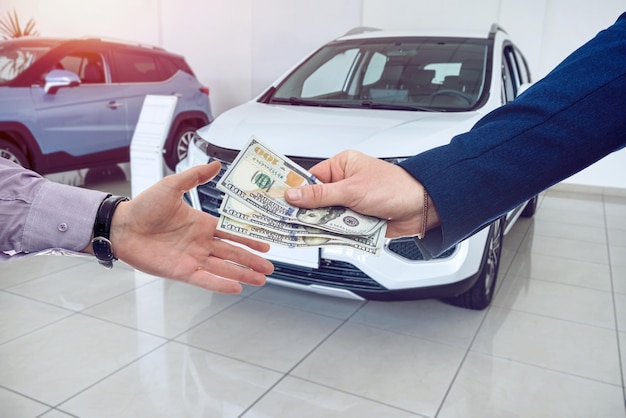 Udany zakup kupujący daje dolary sprzedawcy w nowoczesnym salonie samochodowym