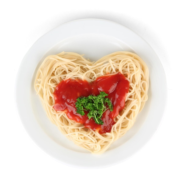 Ugotowane spaghetti starannie ułożone w kształcie serca i polane sosem pomidorowym, na białym tle