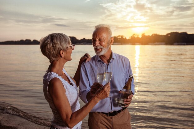 Ujęcie czułej pary seniorów pijącej szampana nad rzeką