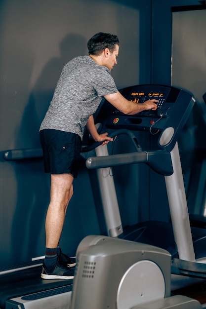 Ujęcie mężczyzny w średnim wieku przygotowuje się do biegania na bieżni na siłowni.
