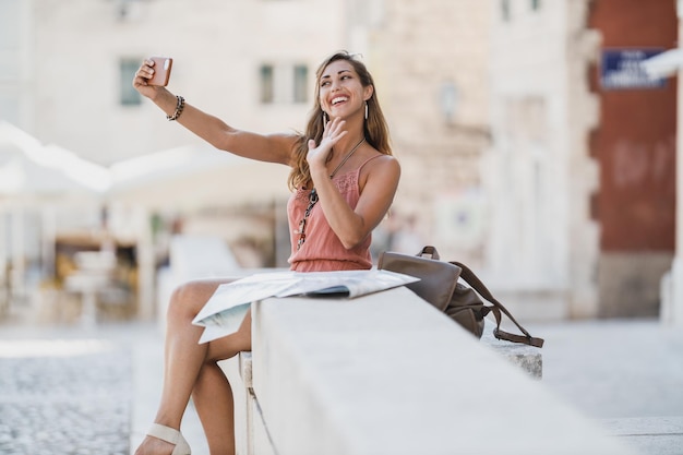 Ujęcie Młodej, Wesołej Kobiety Robiącej Selfie Smartfonem Podczas Zwiedzania Obcego Miasta.